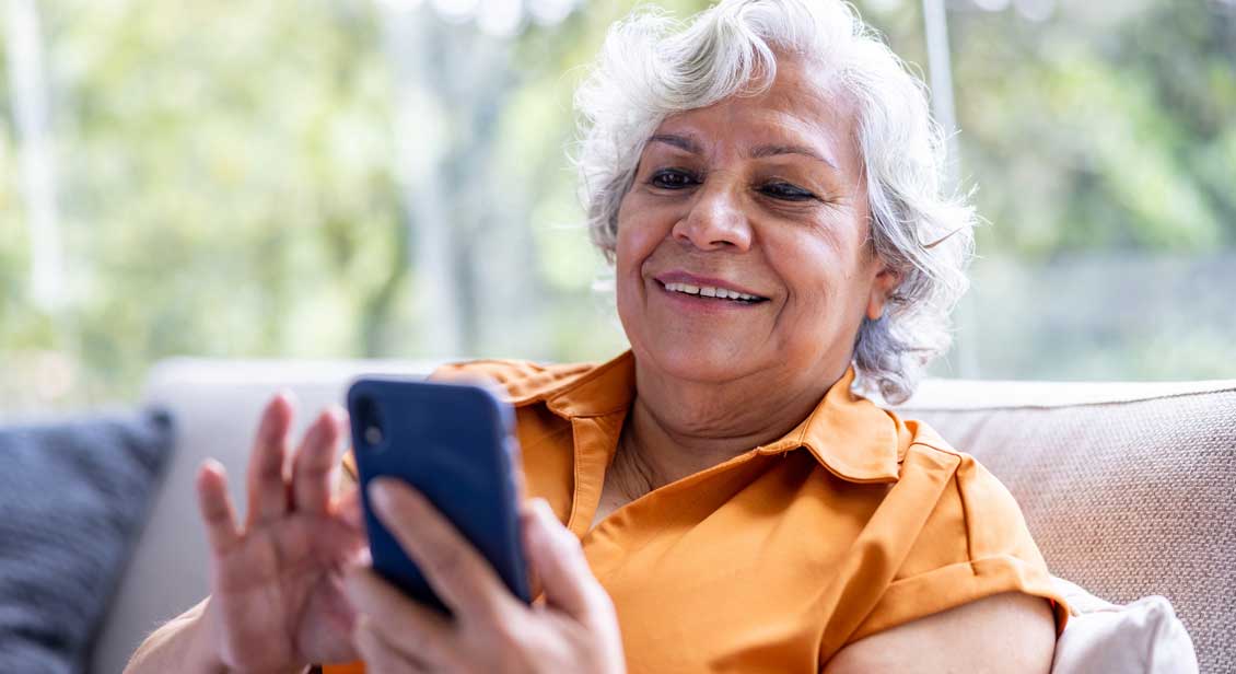 A older woman interacts with apps on a mobile phone.