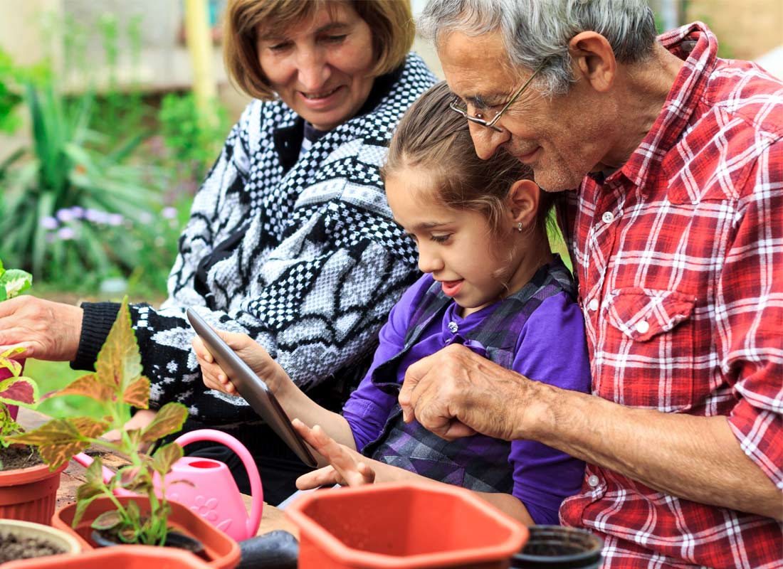 Grandparents enjoy some time in the garden using a tablet with their granddaughter