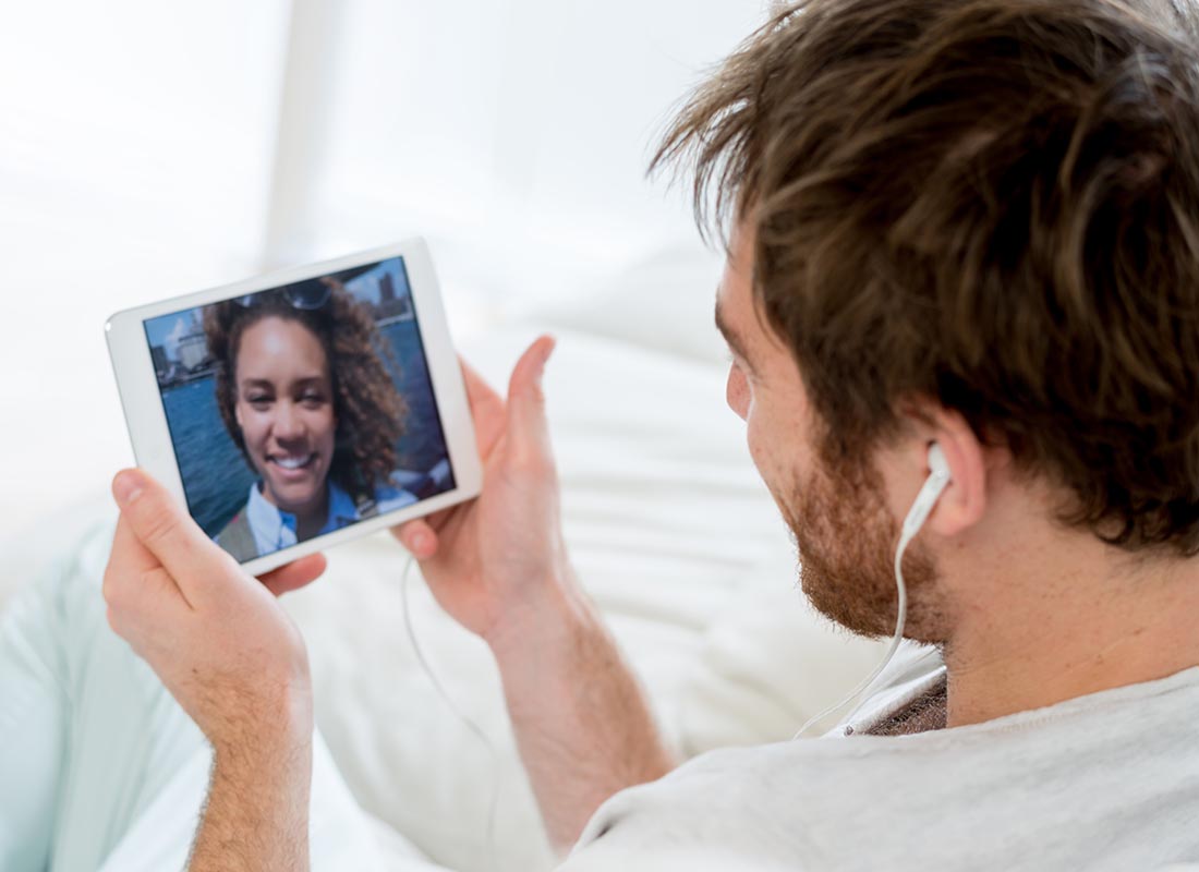 Two friends video chatting to each other using a tablet and headphones