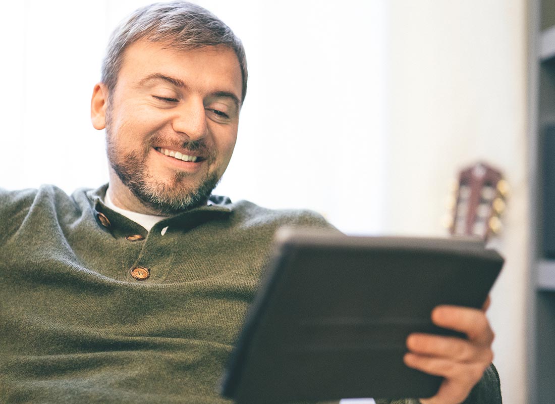 A man relaxing at home using his tablet to Skype his friends