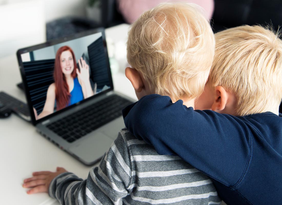 Two children saying hi to their mum over the internet