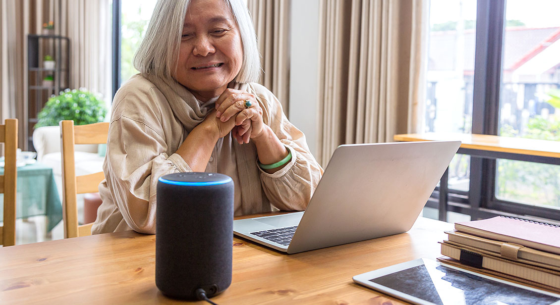 Asian senior women working with laptop computer and using smart speakers while setting in living room