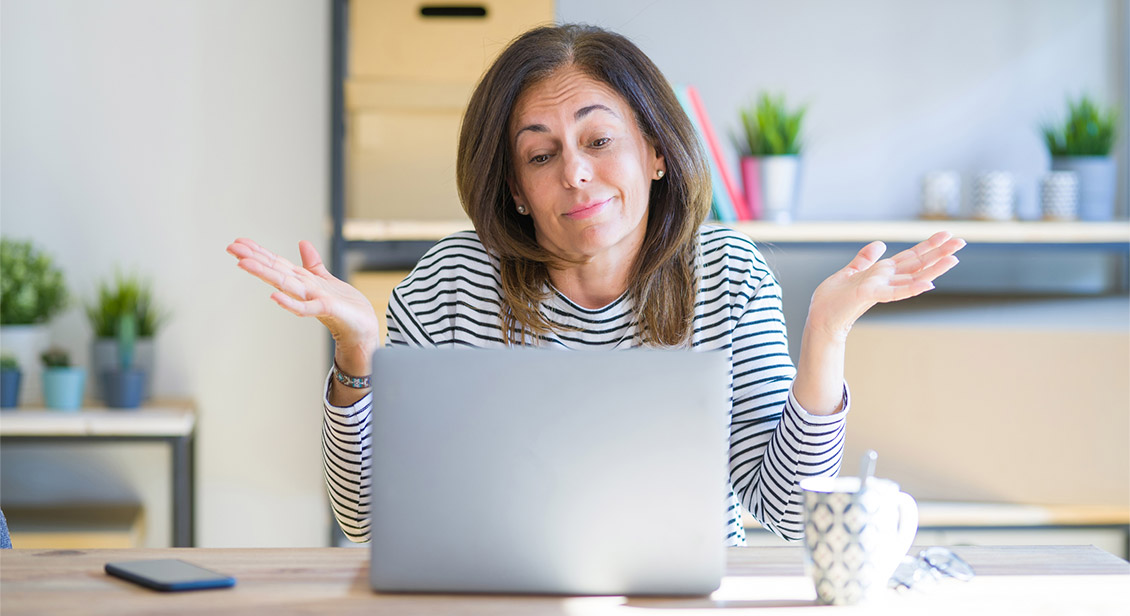Middle age senior woman using computer laptop with a confused expression and hands raised.
