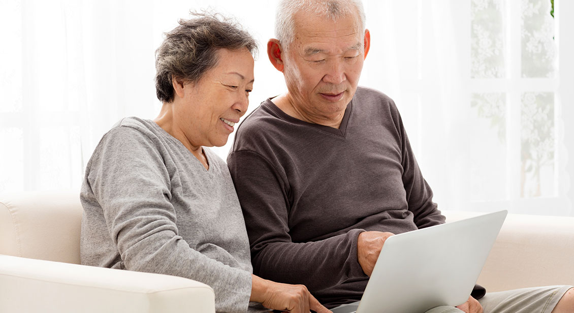 Happy Senior Couple Using Laptop on sofa