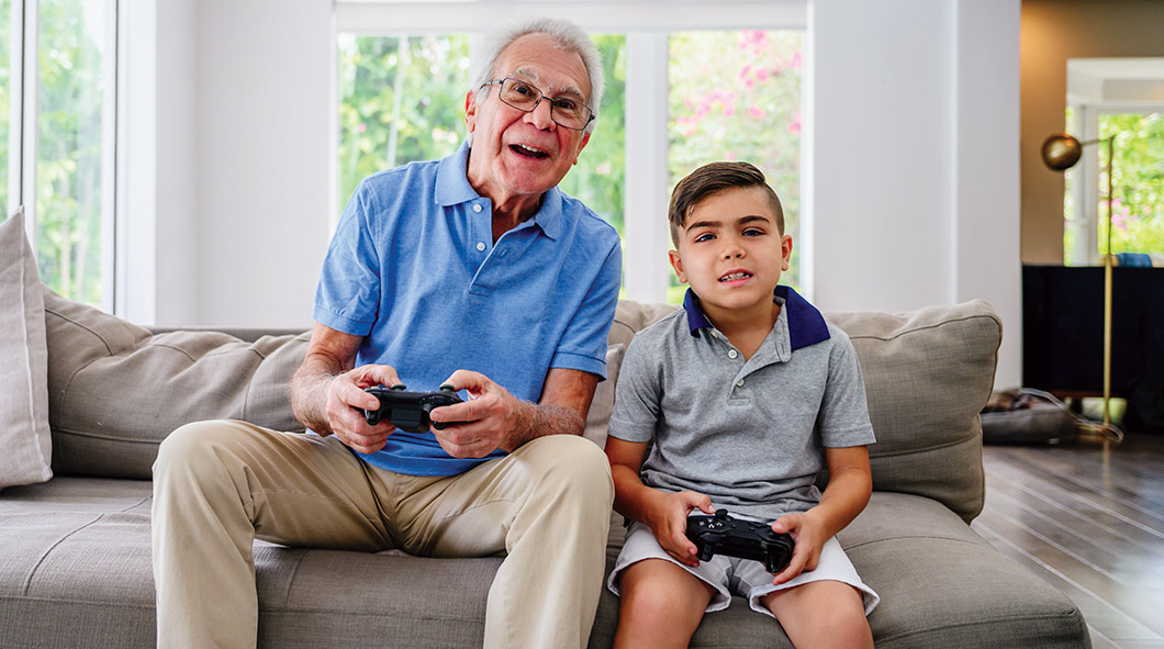 Image of grandparent playing video game with grandchild
