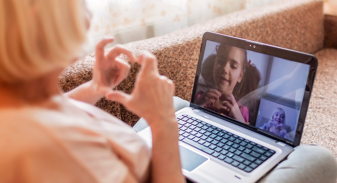 Grandmother and Grand Daughter on a video call making love heart shapes with their hands