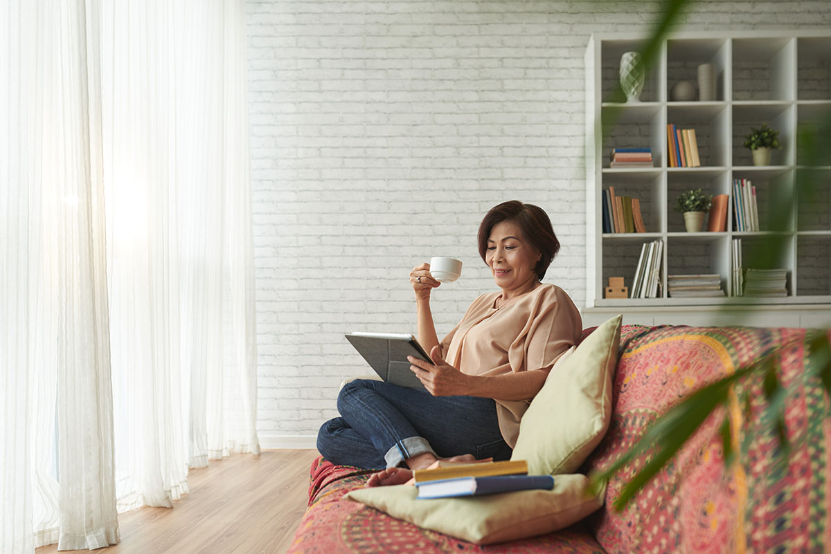 A lady relaxes with a cuppa and browses the internet.