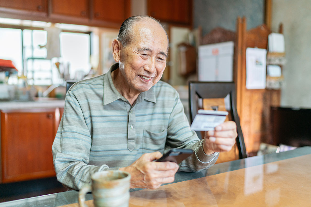 man sitting at table with smart phone and credit card