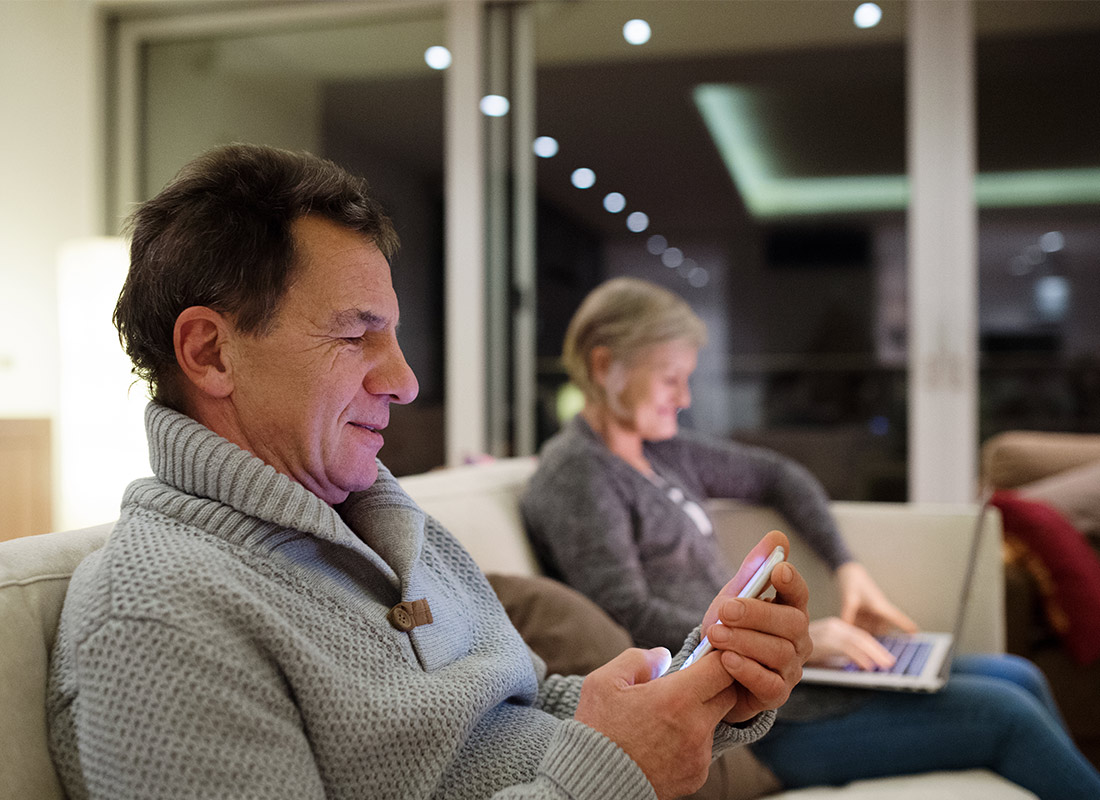 A couple relaxing with their computer and mobile phone