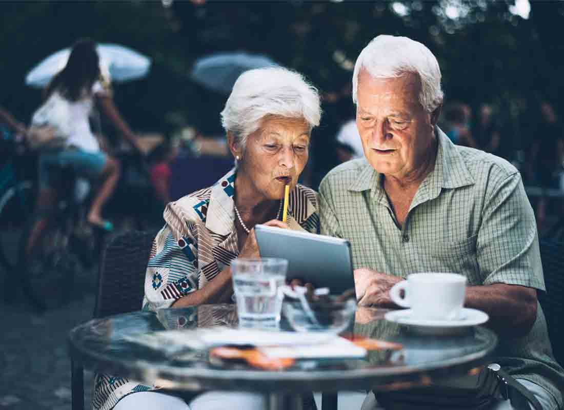 A holidaying couple enjoying a coffee and using their tablet device to catch up with family back home in Australia
