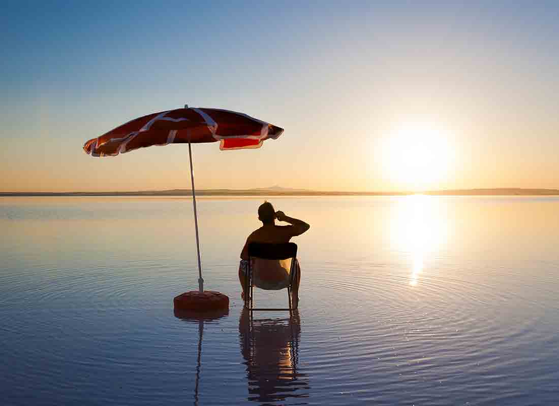 A holidaymaker relaxing on a beach while calling home