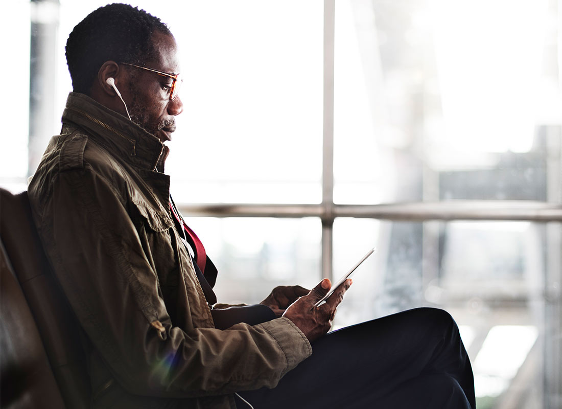 A traveller listening to music on his device before boarding his flight