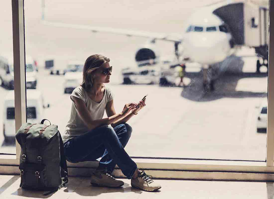 A passenger in an airport departure lounge switches her phone to Flight Mode