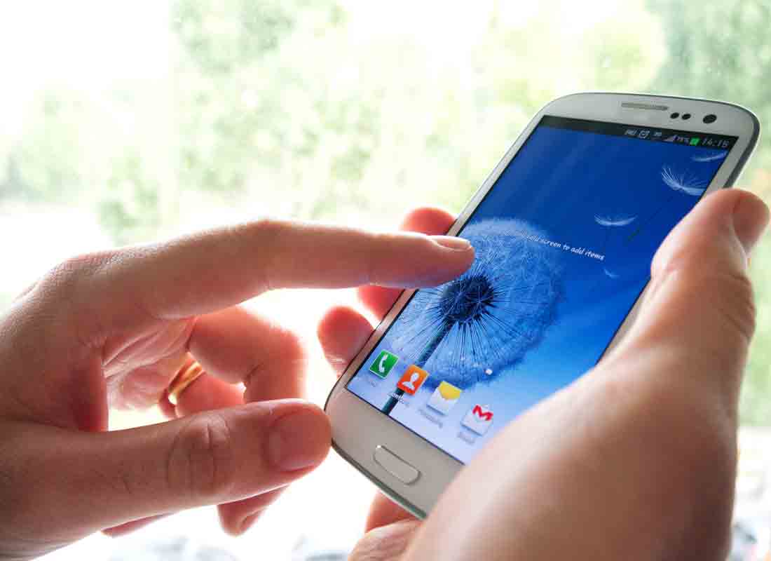Close-up image of a hand tapping on a smartphone touchcreen.