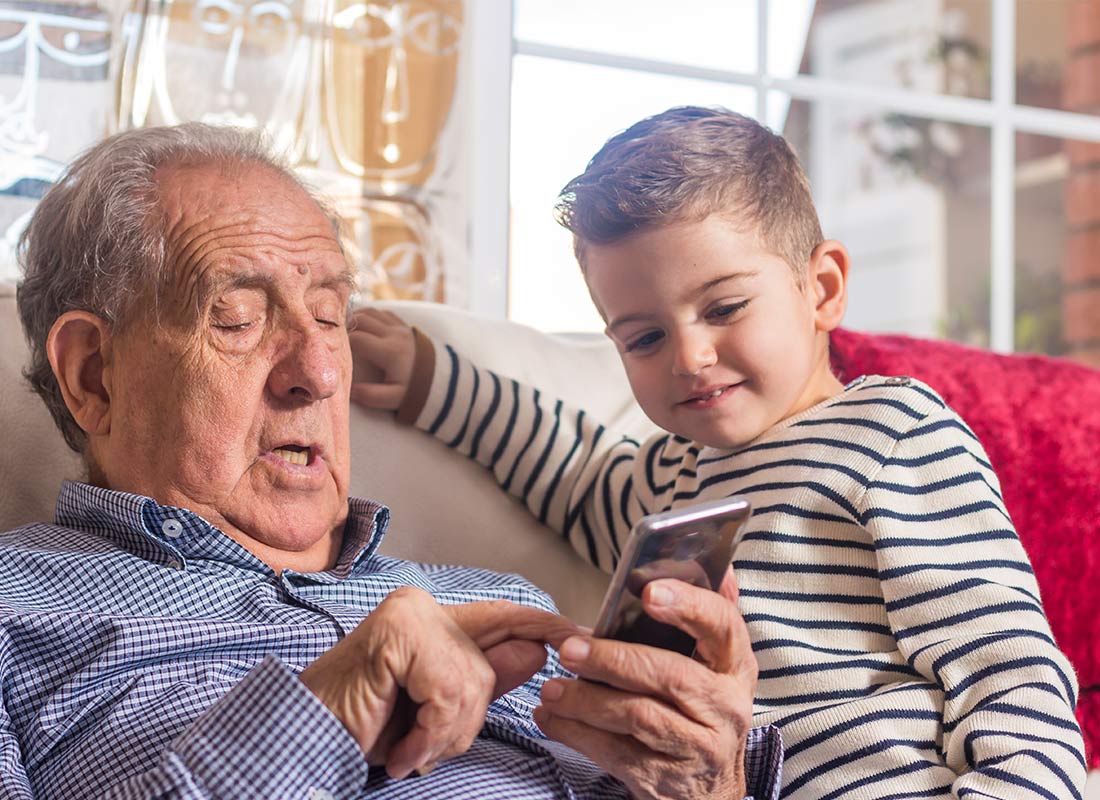 A grandfather and child enjoying using a mobile phone together