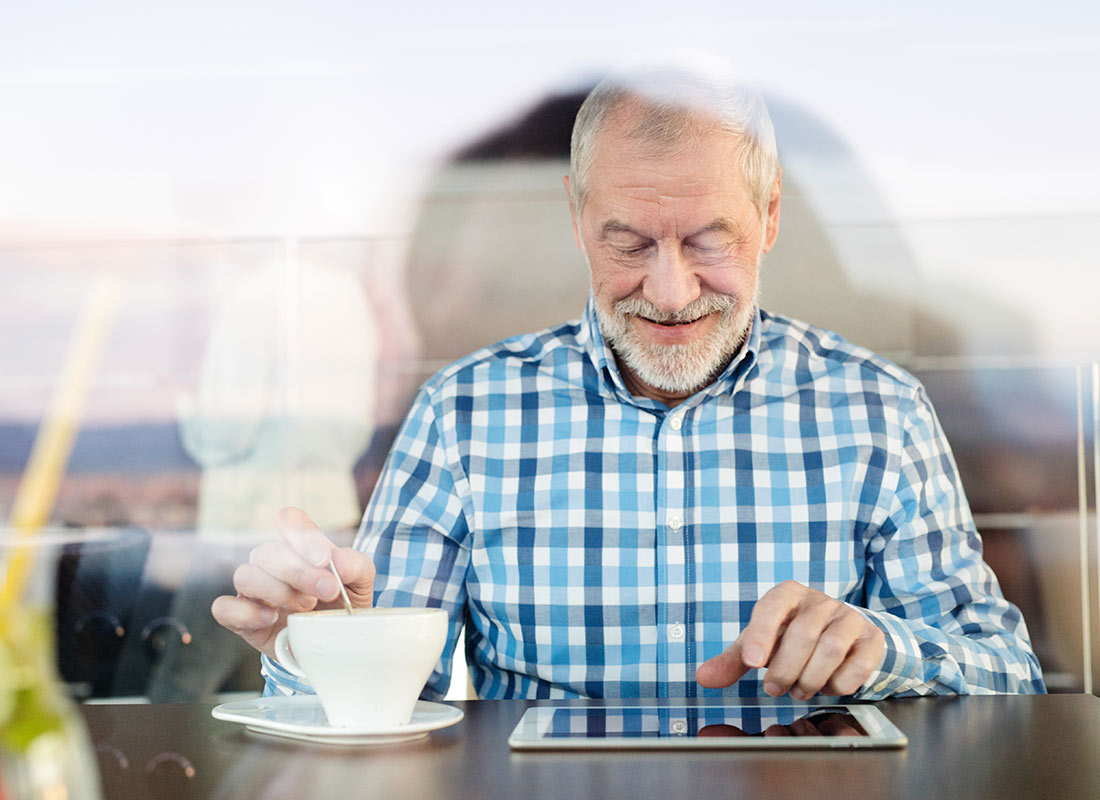 A grandfather enjoying relaxing with a tablet device at a cafe