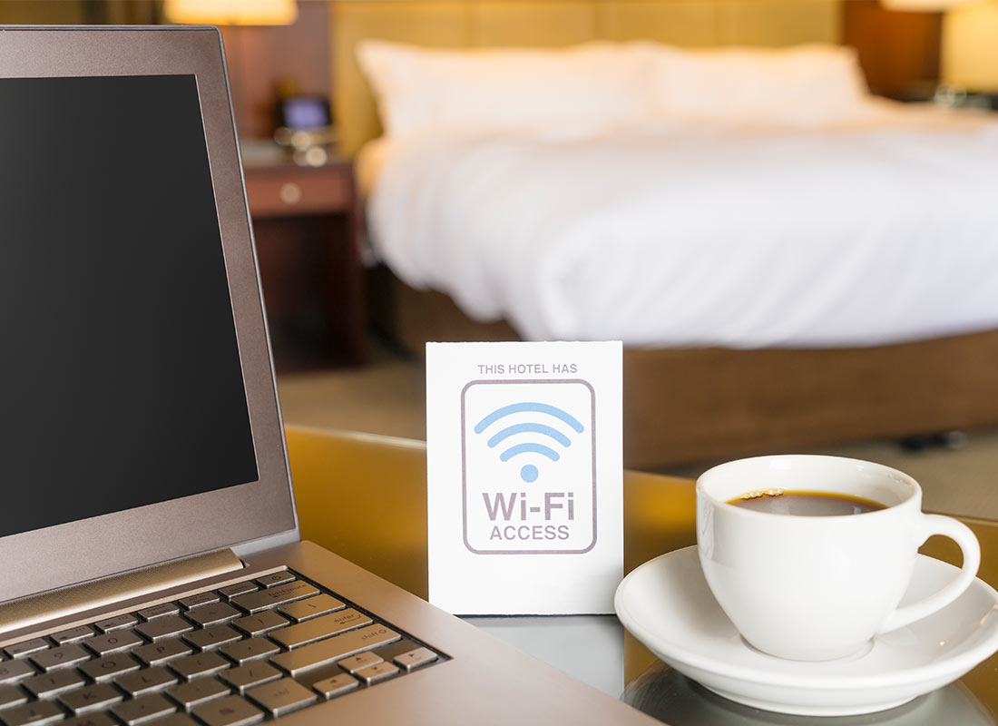 A hotel room with their Wi-Fi information card next to a cup of tea on the desk
