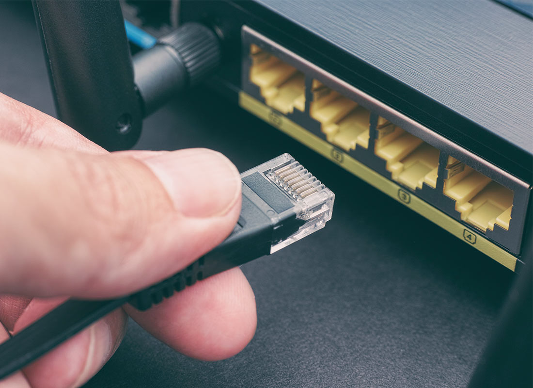 A home Wi-Fi router with a cable about to be plugged into it.