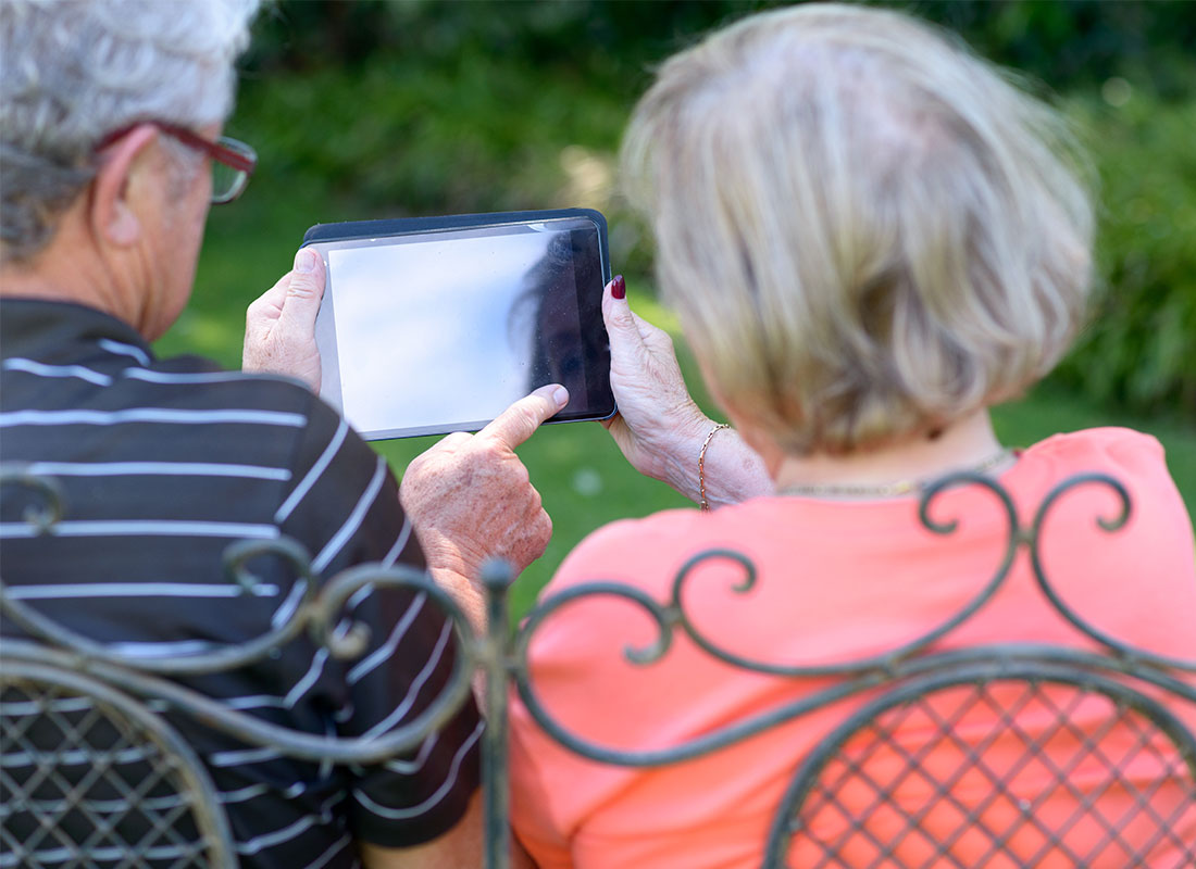 An older couple in the garden reading documents on their tablet using the home Wi-Fi network.