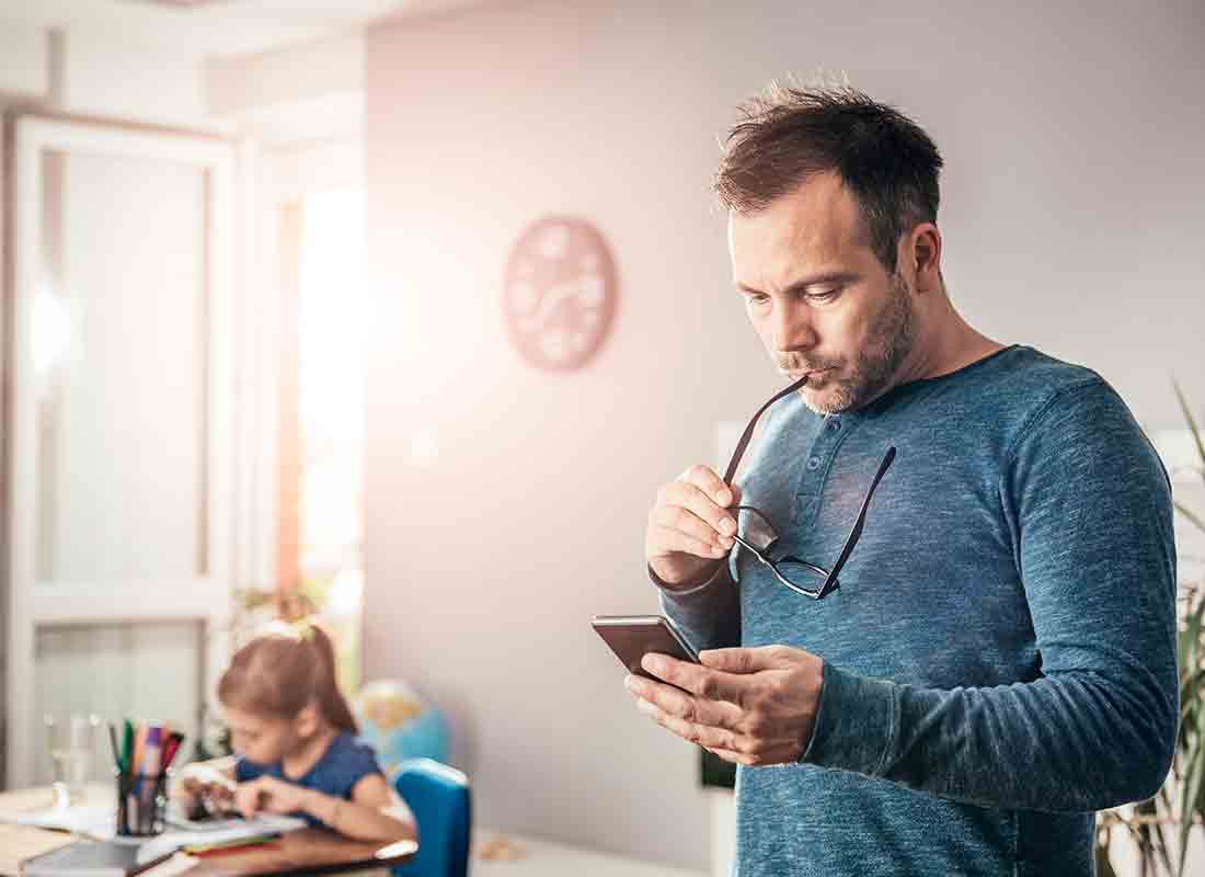 A dad checks an answer he's given to his daughter for her homework on his mobile phone