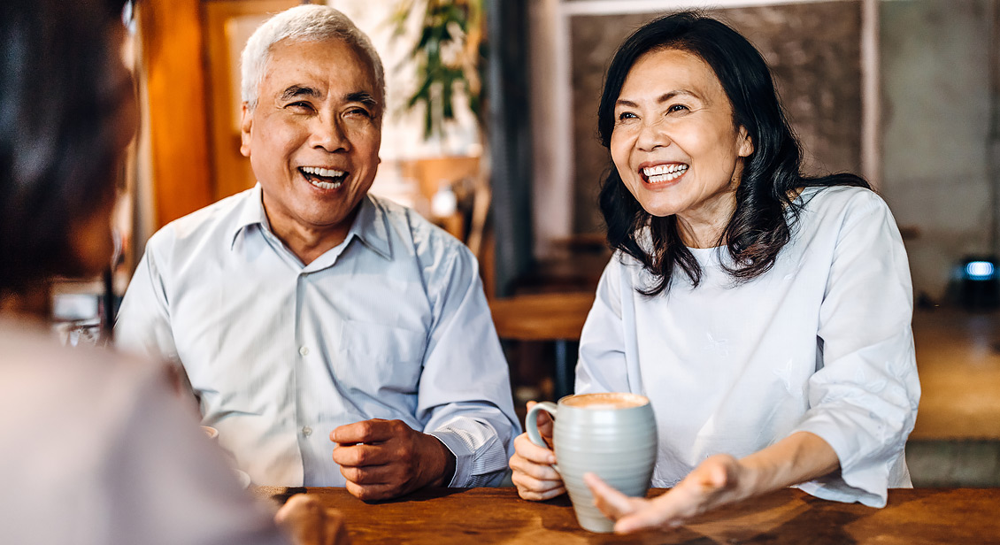 middle aged male and female asian Australians smiling while enjoying a coffee