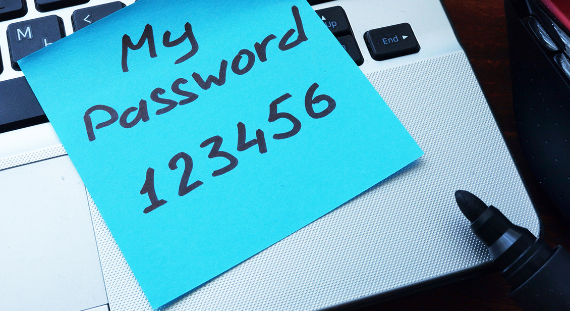 Password and login details on a aqua green coloured post it note which is stuck to a laptop