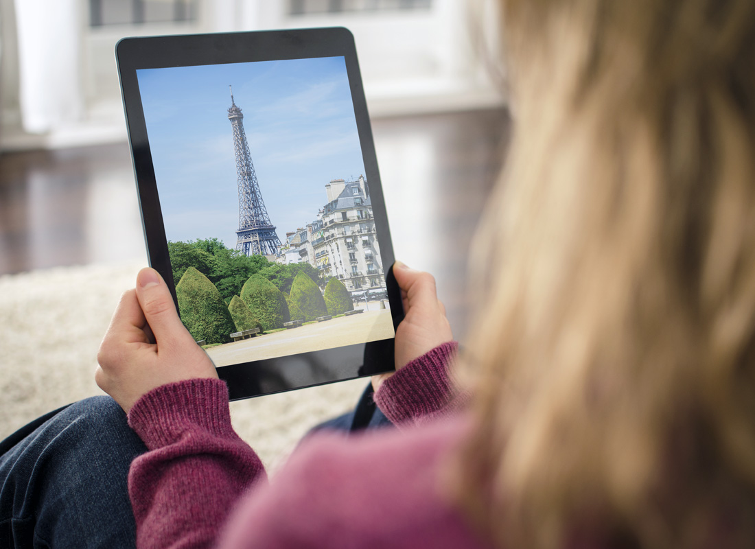 A photo of a woman holding a tablet with the Eiffel Tower in Paris pictured on it.