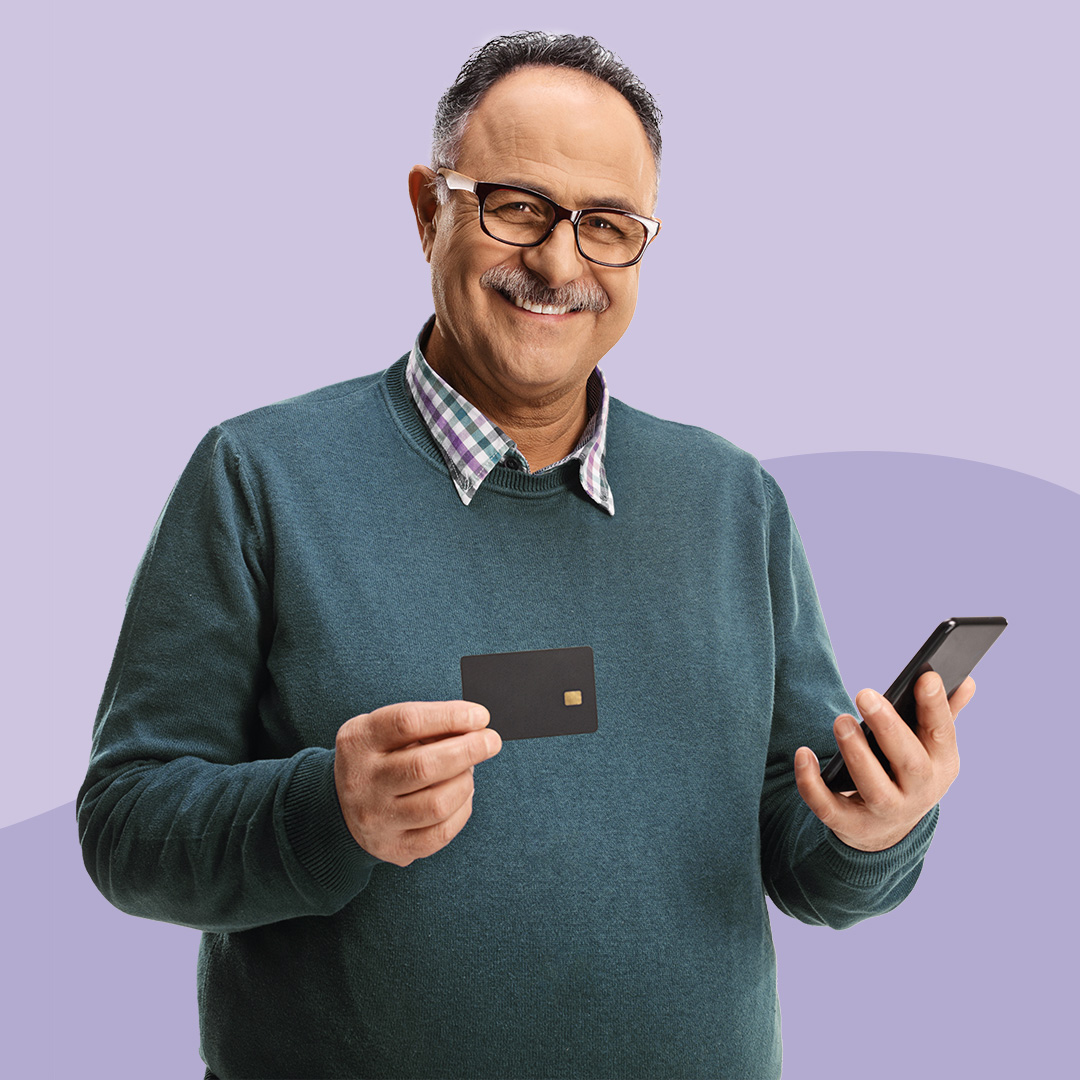 A man holding a mobile phone in one hand and a credit card in the other