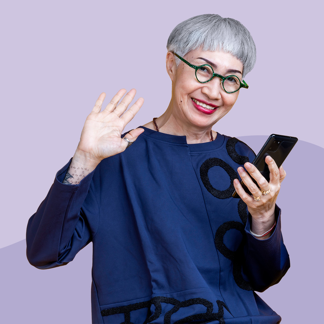 A woman holding a smart phone, waving a viewer.
